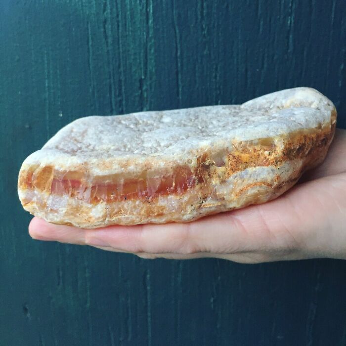 A hand holds a large rock with an amber-like core, a confusing pic.