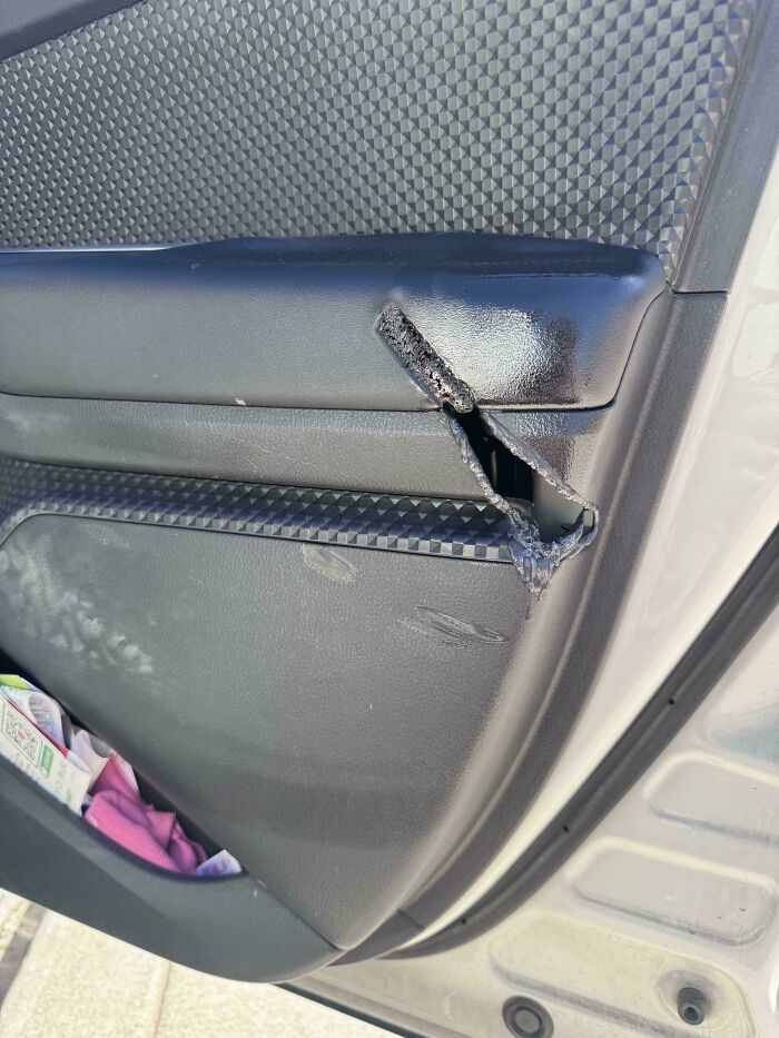 A car door panel with a dangerous, unnecessary, and sharp rip, showing visible damage and scratches.
