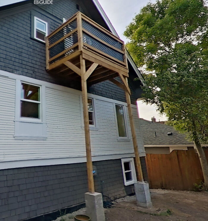 A poorly constructed wooden balcony extends from a house, supported by thin stilts, a dangerous thing people did.