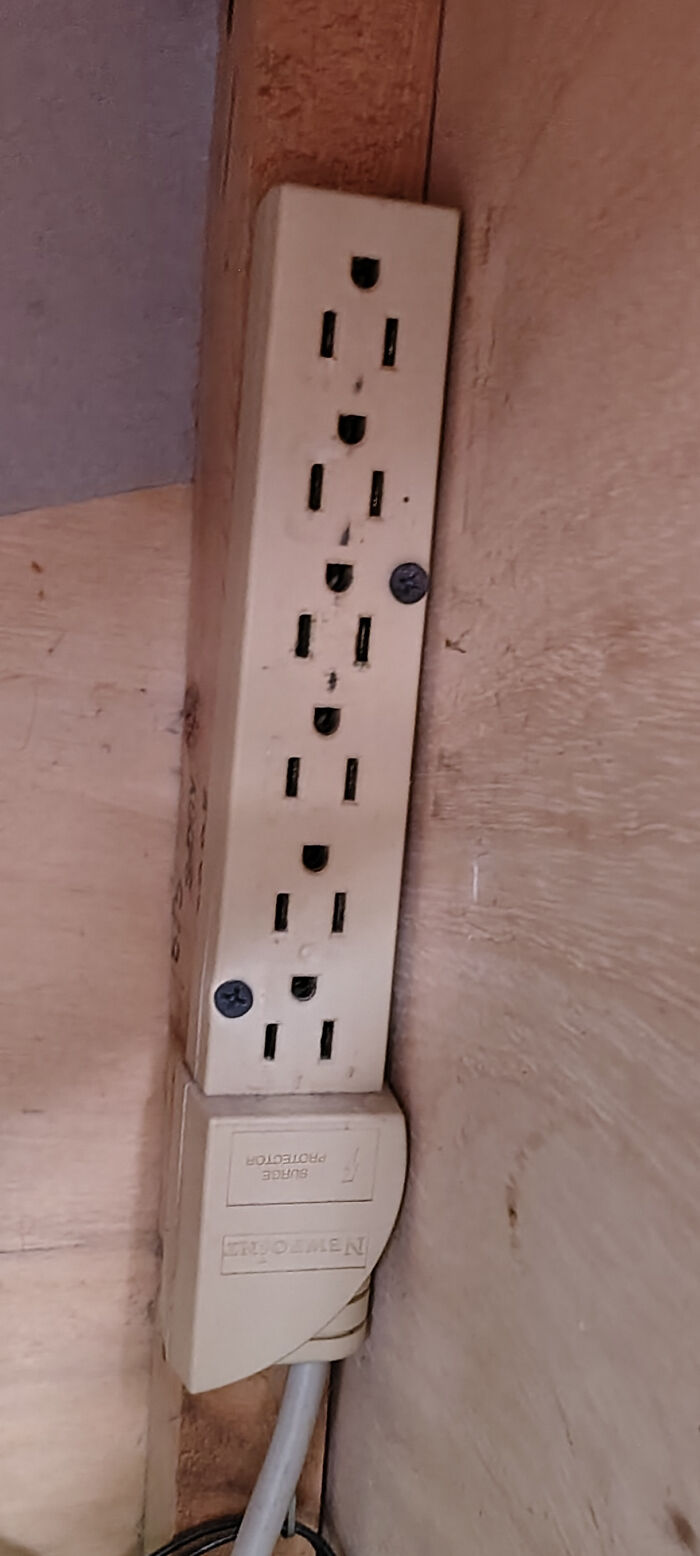 A dangerous power strip with multiple outlets, haphazardly mounted, posing an unnecessary electrical hazard.