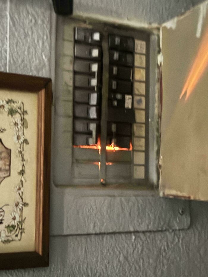 A dangerous electrical panel with visible sparks and fire inside, indicating a serious electrical hazard.
