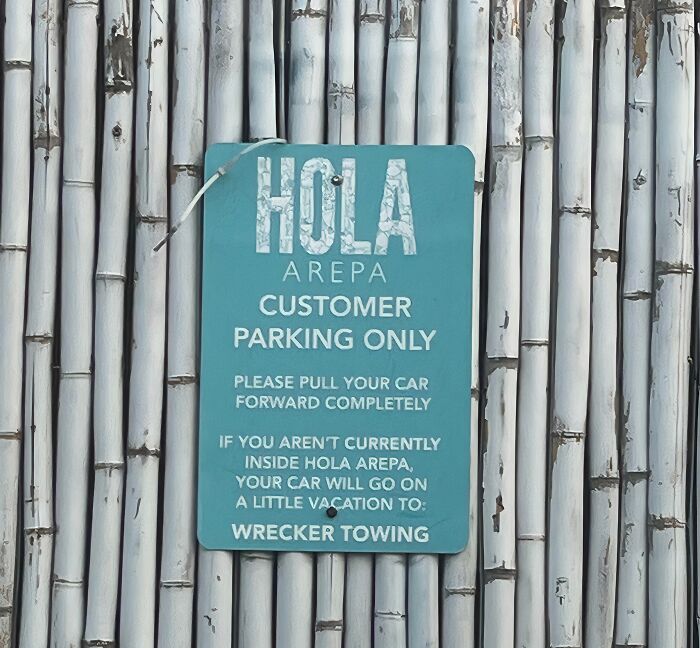 A passive-aggressive note about customer parking at Hola Arepa, threatening towing for unauthorized vehicles.