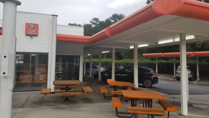 A Little Caesars pizza restaurant, a building pretending to be a drive-through with outdoor picnic tables.