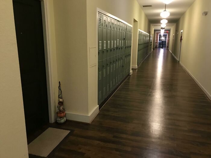 A hallway in a building pretending to be a residential space, with lockers lining the wall, reminiscent of a school.