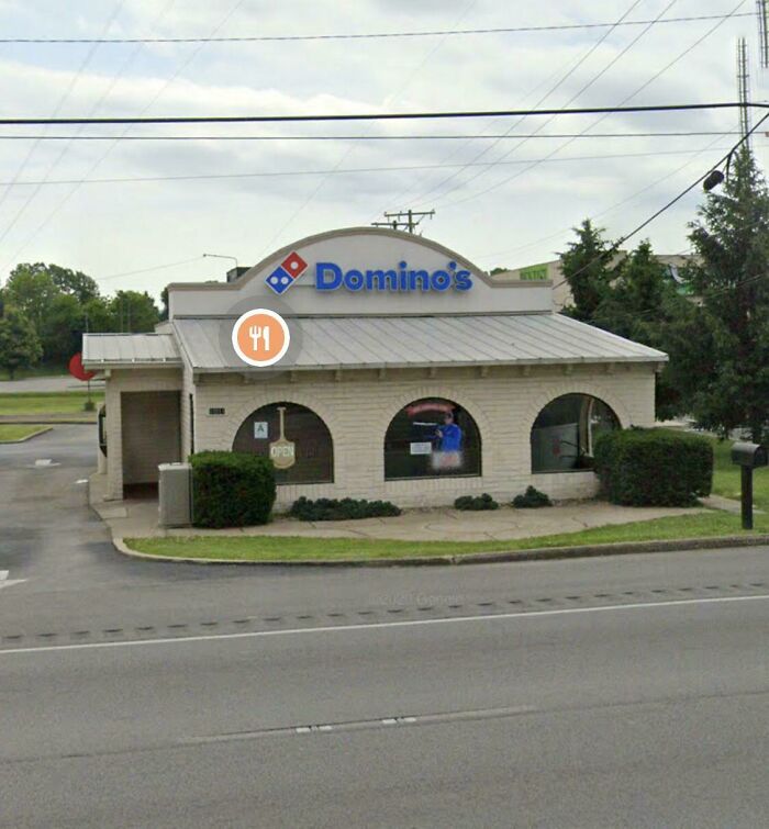A building pretending to be something it is not; a white brick Domino's Pizza with arched windows, formerly another business.