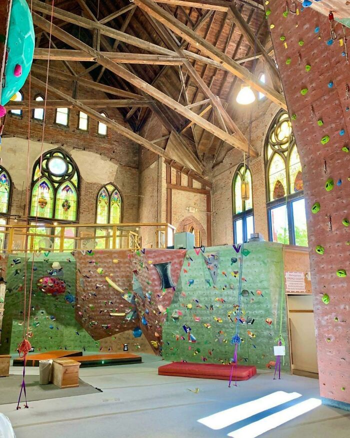 An indoor rock climbing gym inside an old church with stained glass windows, pretending to be something different.