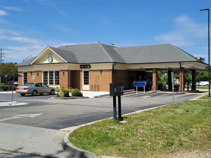 A Starbucks drive-thru building pretending to be a bank, with cars parked and a drive-thru lane.