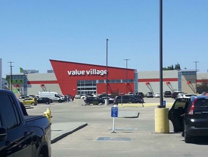 A Value Village store building pretending to be a modern retail center, with a large parking lot and cars.