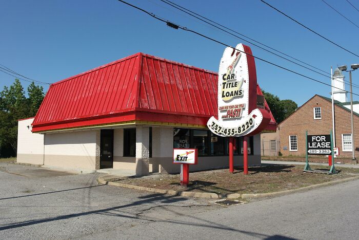 Building with a red roof and a large sign for car title loans, one of many buildings pretending to be something else.