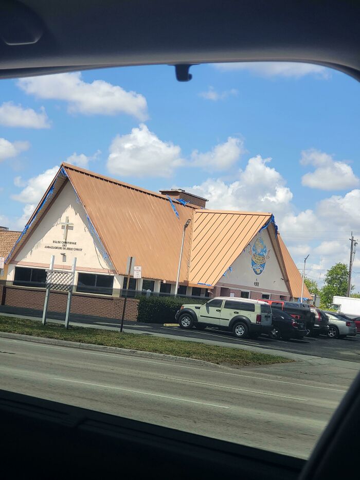 Church building with a brown roof and a cross, one of many buildings pretending to be something else.