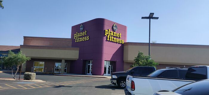 Planet Fitness, a building pretending to be something it is not, featuring its purple exterior and prominent signage.