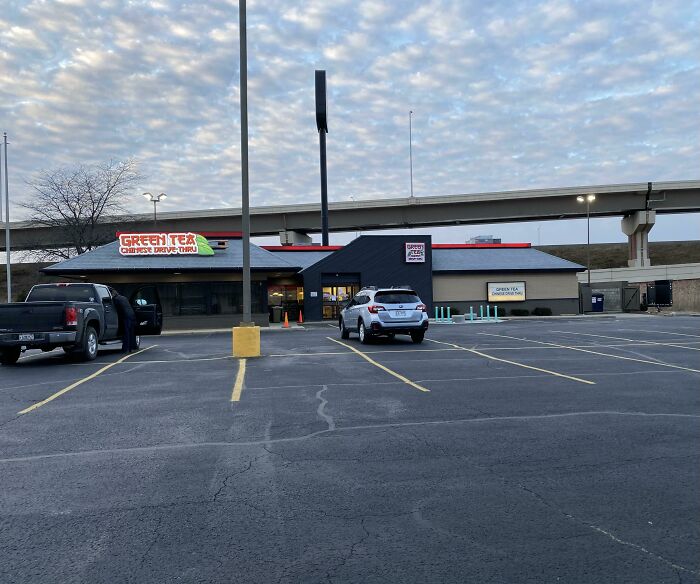 A Green Tea Chinese Drive-Thru in a building pretending to be something it's not, with a large empty parking lot.