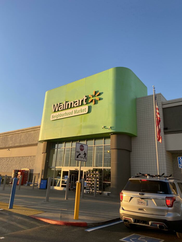 A Walmart Neighborhood Market building pretending to be something it's not, with a large green facade under a blue sky.