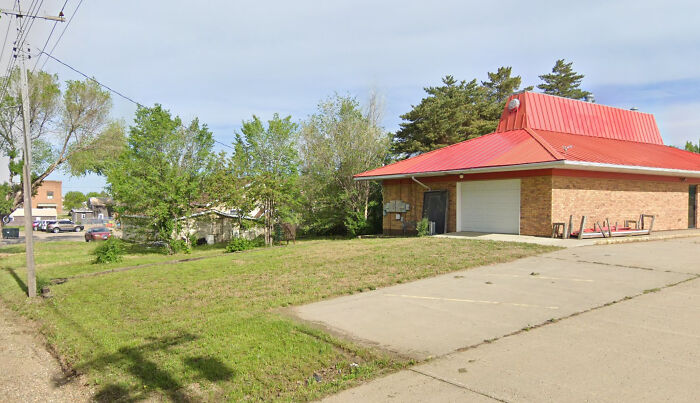 A red-roofed brick building with a drive-thru, seemingly a former fast-food restaurant, one of many buildings pretending.