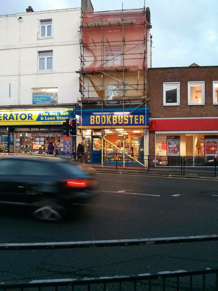 Bookbuster store with scaffolding on the upper floor, a building pretending to be something new or under renovation.