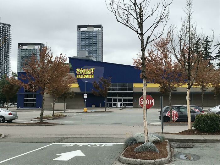 A Spirit Halloween store in a large blue building, a building pretending to be something else with city buildings in background.