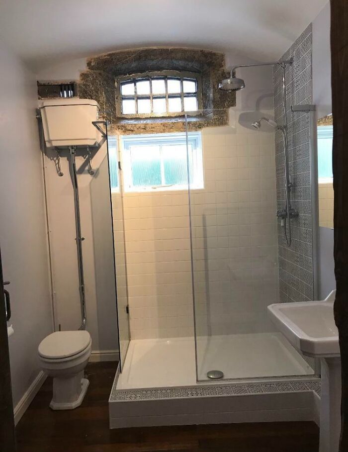 A bathroom with a toilet and shower in a building that is pretending to be something it is not.