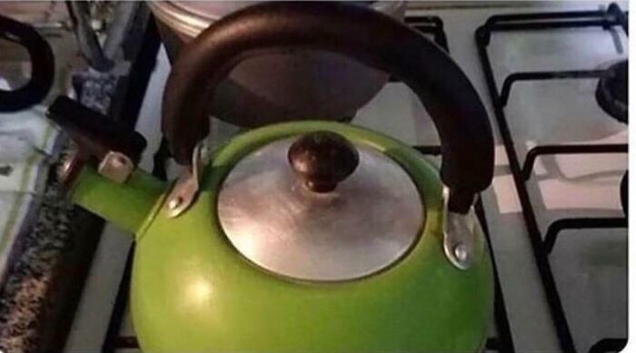 A confusing pic of a green kettle on a stove, featuring an optical illusion that makes it appear like a single, giant eye.