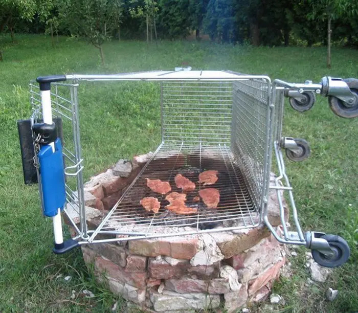 A shopping cart repurposed as a grill over a fire pit, demonstrating clever solutions with random junk.