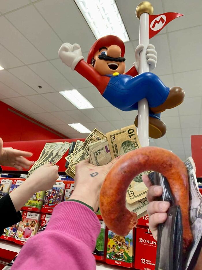 A chaotic scene with a Mario statue, hands holding money and a sausage, in a store, one of those pics that people cannot explain.