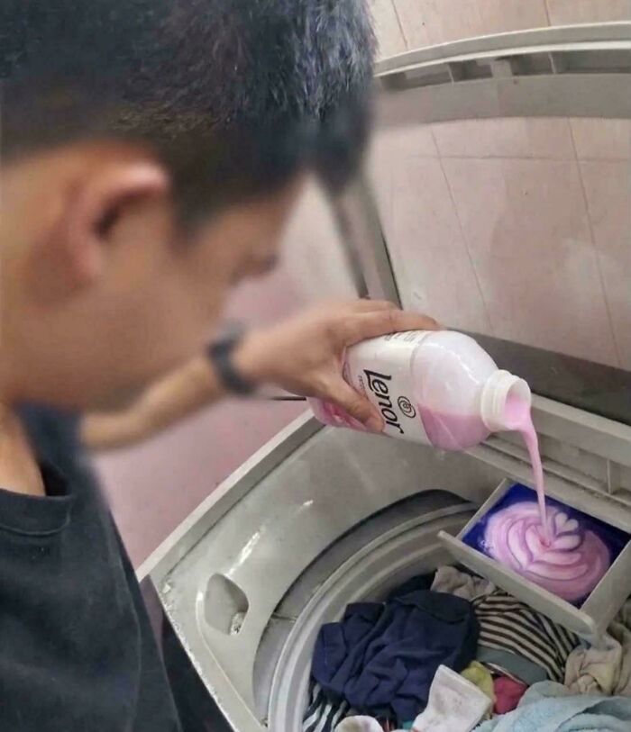 A man pouring a large amount of pink fabric softener into a washing machine, creating a swirl. A pic people cannot explain.