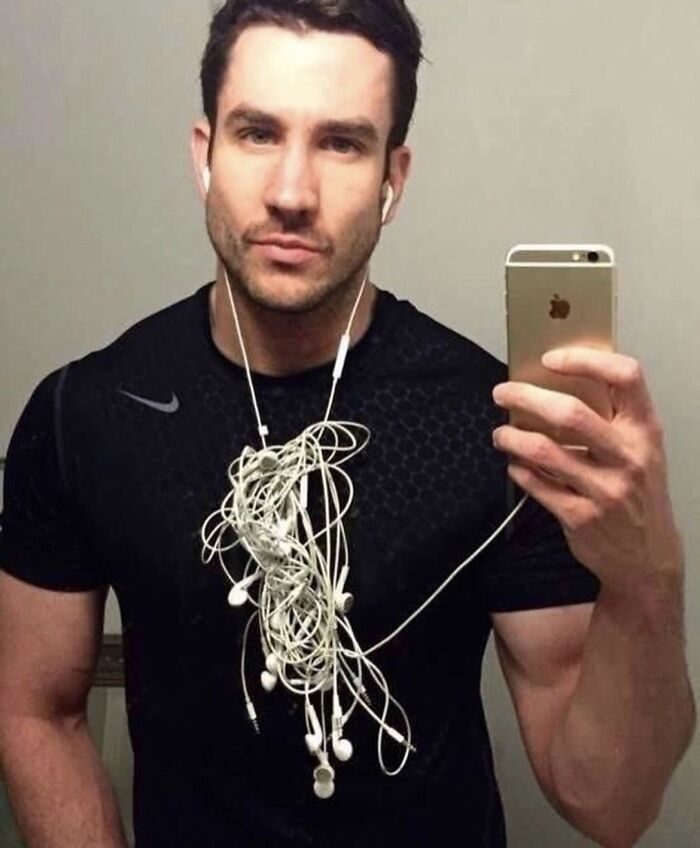 A man takes a selfie with tangled earbuds around his neck, one of many pics people cannot explain.