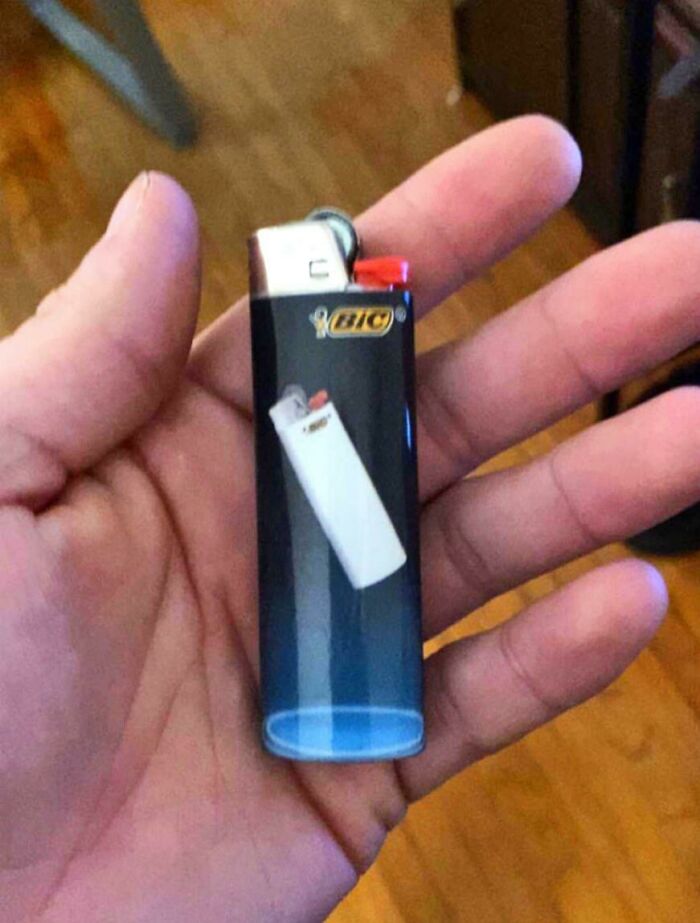 A hand holding a BIC lighter with a picture of another BIC lighter on it, an odd image people cannot explain.