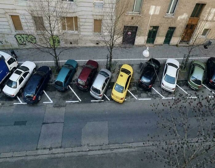 An aerial view of a row of cars parked at unusual, diagonal angles, creating an unexplainable sight for many people.
