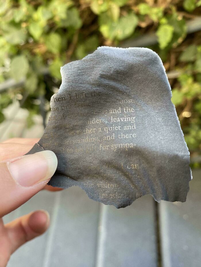 A hand holding a burnt piece of paper with text, an example of ephemera showing how the past has changed.