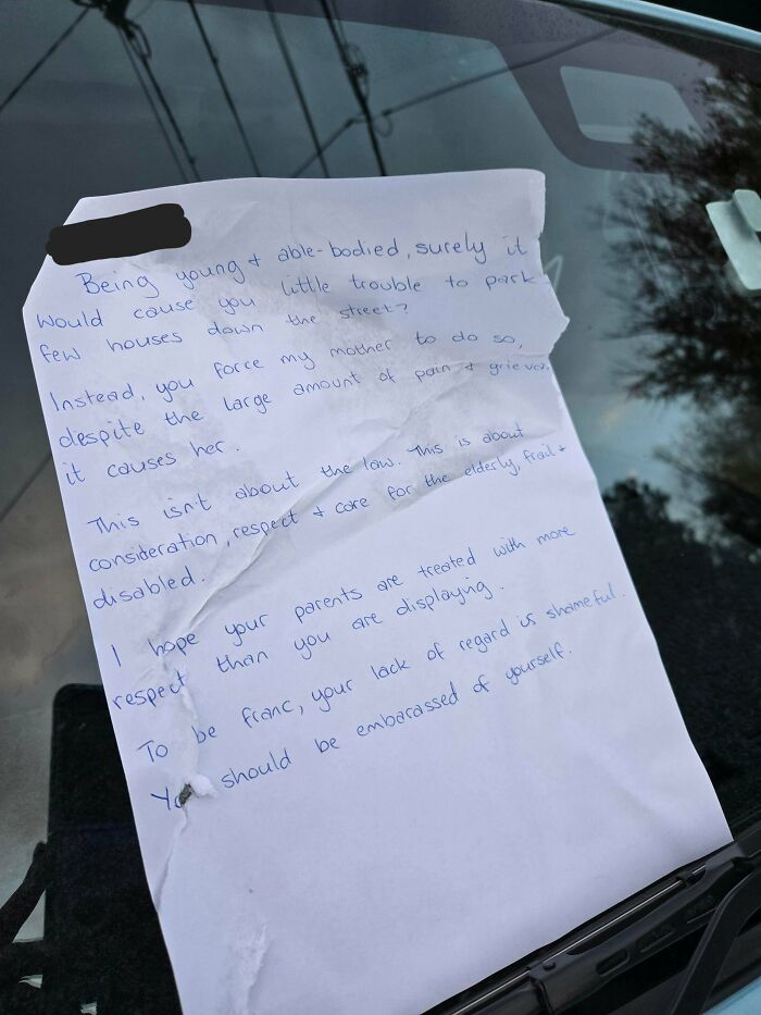 A note on a windshield regarding bad parking, showing how jerk neighbors disregard common sense.