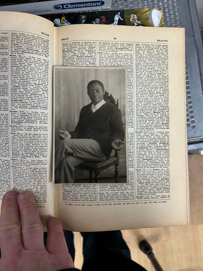 A black and white photo of a man tucked into an old dictionary, illustrating ephemera and how the past has changed.