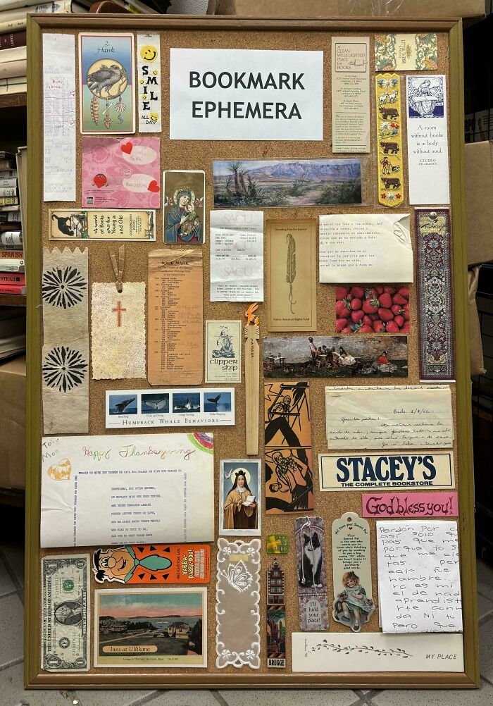 A cork board filled with various bookmark ephemera, including postcards, old notes, and small advertisements.