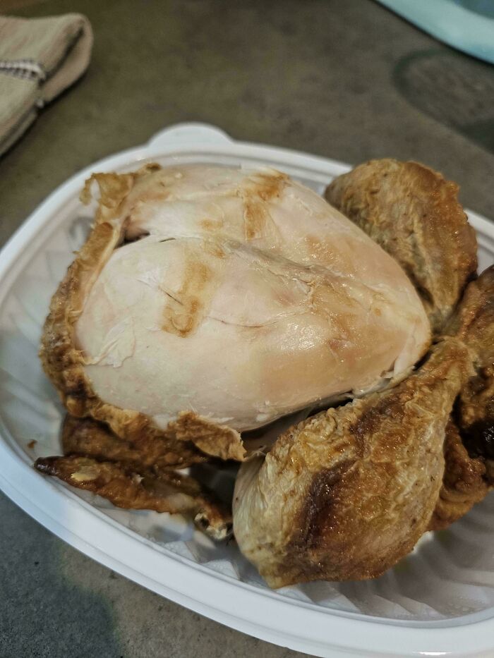 A close-up of roasted chicken in a white container, highlighting the breast and drumsticks. A roasted chicken can make being a cat lady more attractive.