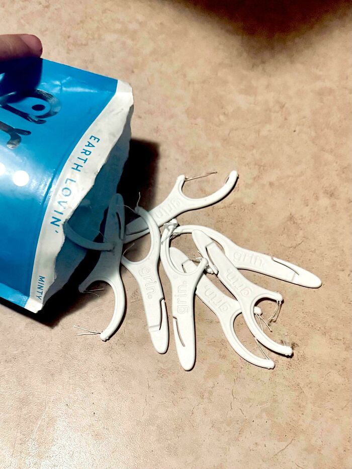 A pile of white dental floss picks spilling out of a blue package, illustrating the challenges parents face.
