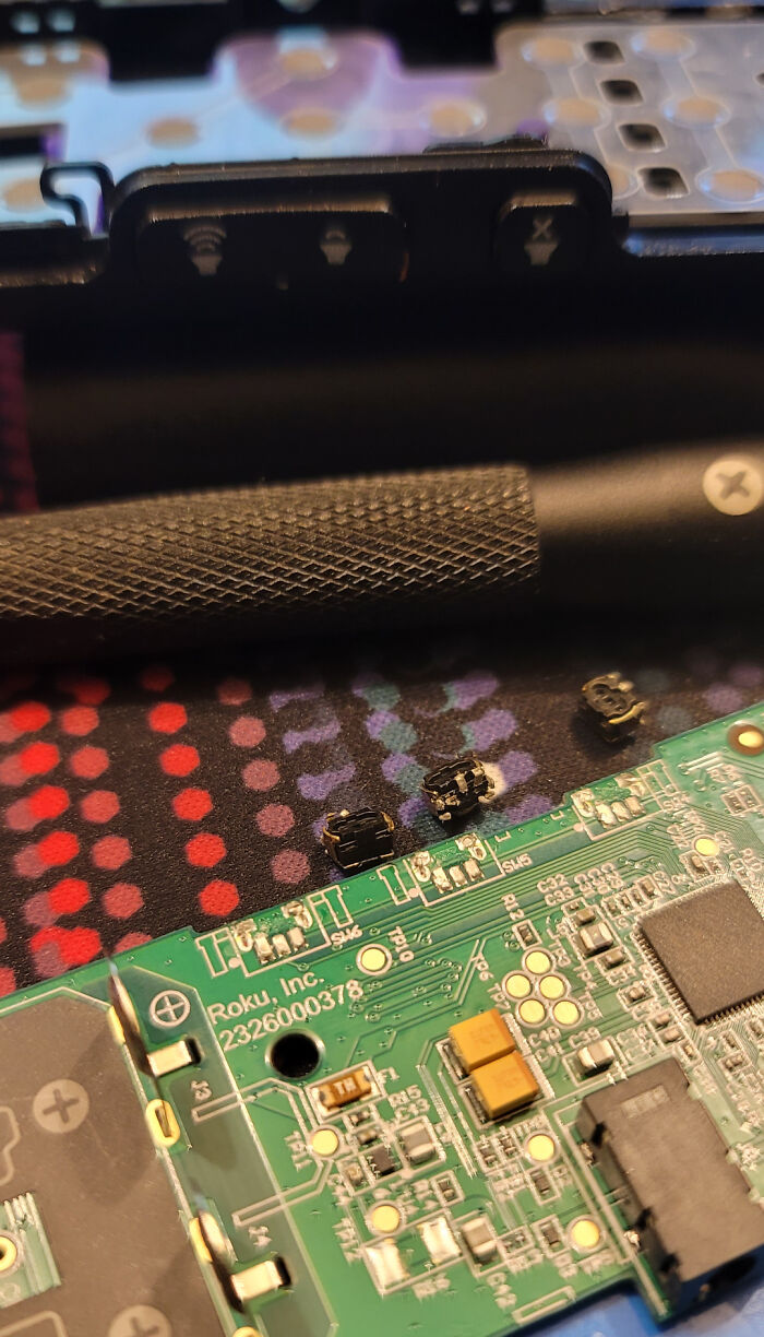 Tiny, detached buttons from a device next to a circuit board, a common outcome of children's curiosity for parents.