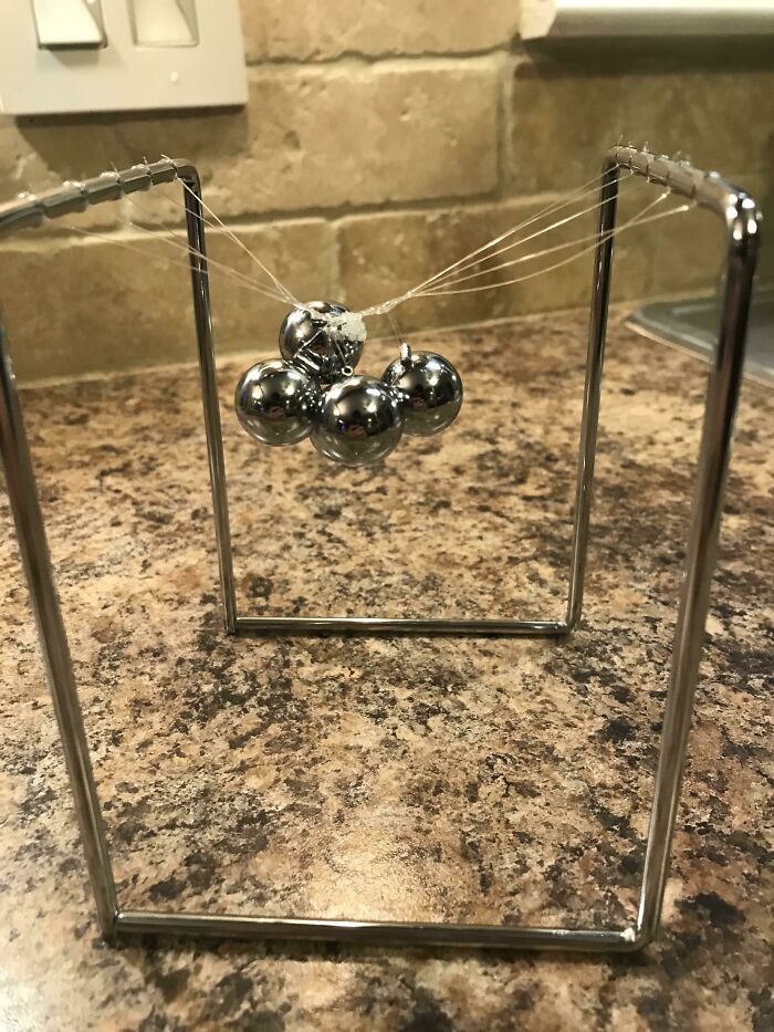 A Newton's cradle with its balls tied in a knot, showing a moment that makes parents question their choices.