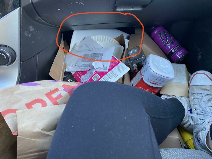 A car interior filled with trash and fast food, making becoming a cat lady look attractive.