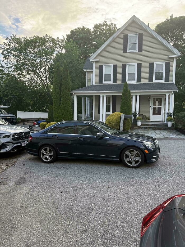 A car parked poorly, blocking a driveway and showing jerk neighbors parking issues.