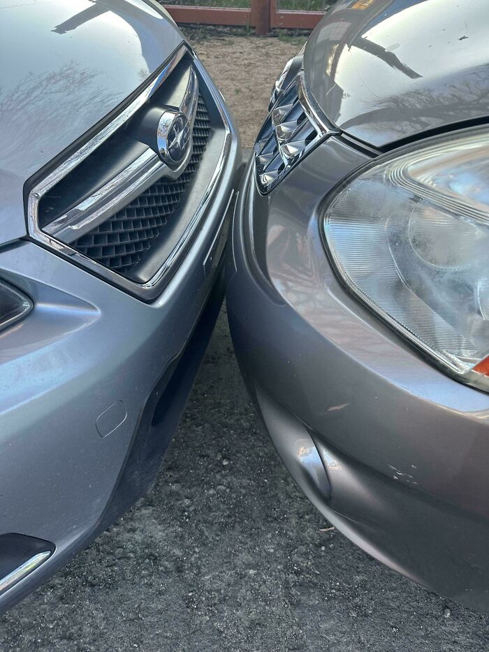 Two car bumpers are nearly touching, showing a close-up of terrible parking and common sense failure.