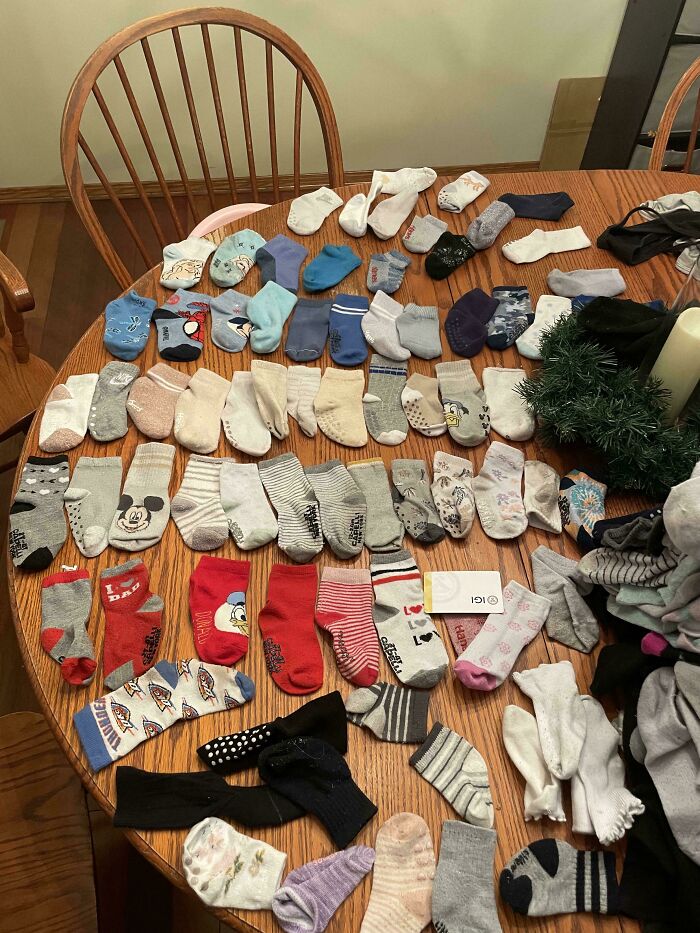 A round table covered with mismatched baby socks symbolizes parents tackling endless laundry tasks.