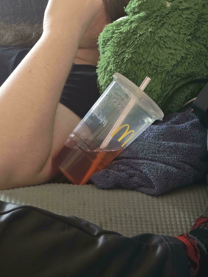 A McDonald's cup with a drink spilled onto the couch, making becoming a cat lady look attractive.