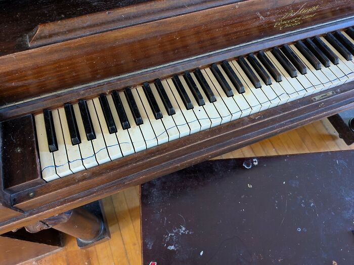 A close-up of a damaged piano keyboard with several keys drawn on, highlighting a funny parenting moment.