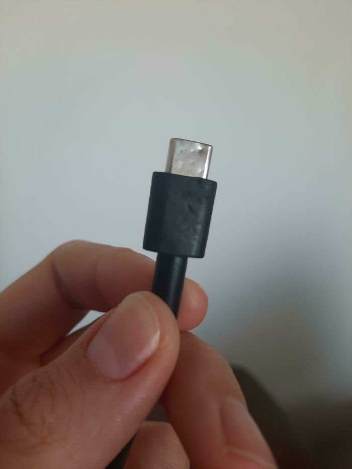 A hand holding a damaged USB-C cable, showcasing an everyday item parents might encounter broken.