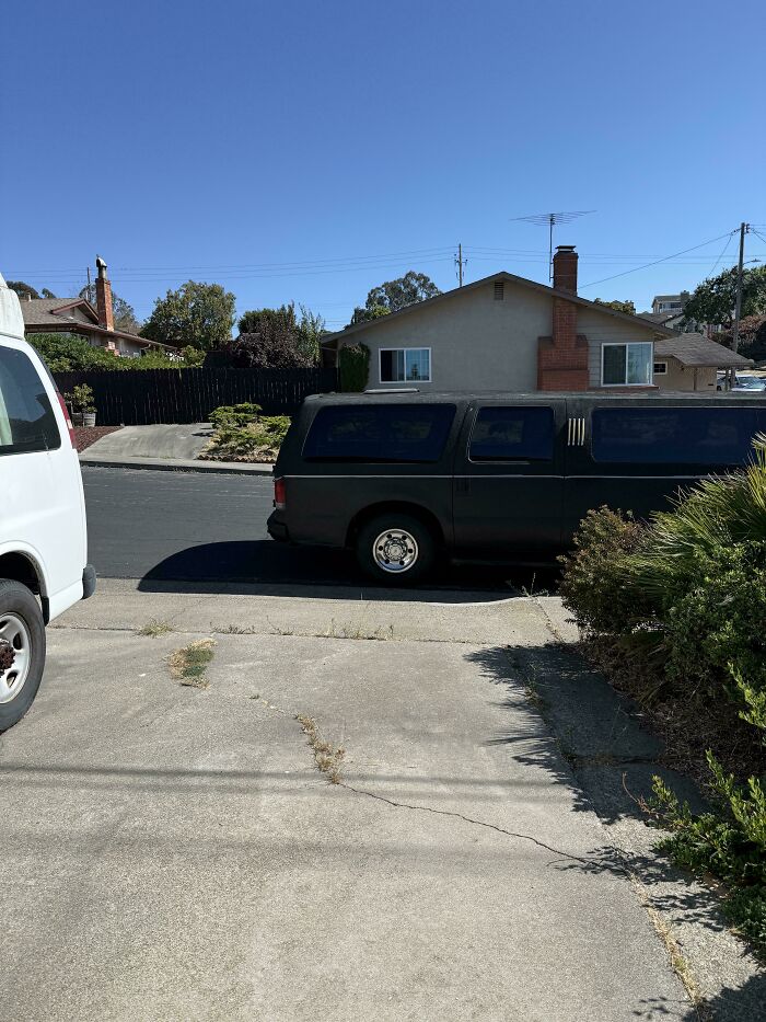 A large black vehicle poorly parked, blocking a driveway, illustrating issues with jerk neighbors and their parking.