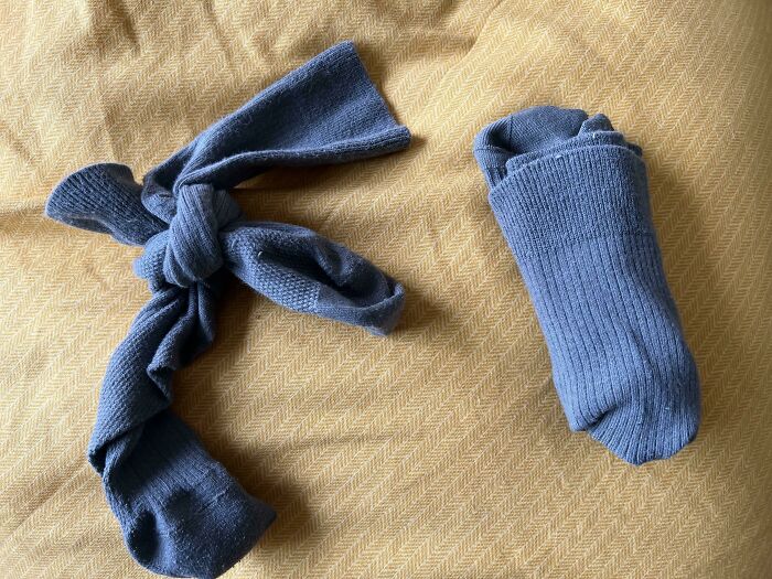 A pair of socks, one tied in a knot, on a yellow blanket, exemplifies why becoming a cat lady is attractive.