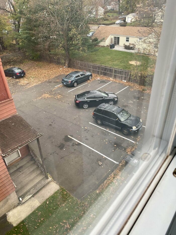 An aerial view of a parking lot where several jerk neighbors cars are poorly parked across multiple spaces.