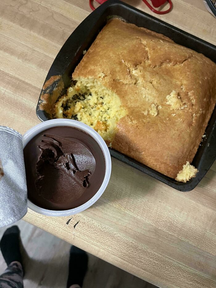 A partially eaten cake next to a container of chocolate frosting, showcasing a relationship struggle leading to a cat lady life.
