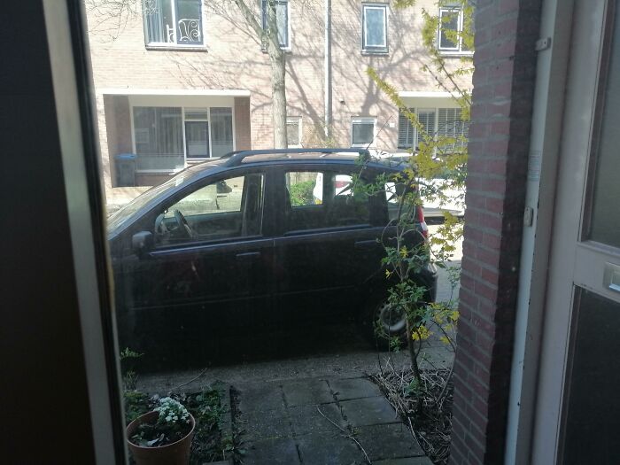 A black car parked directly in front of a door, showing bad parking by neighbors.