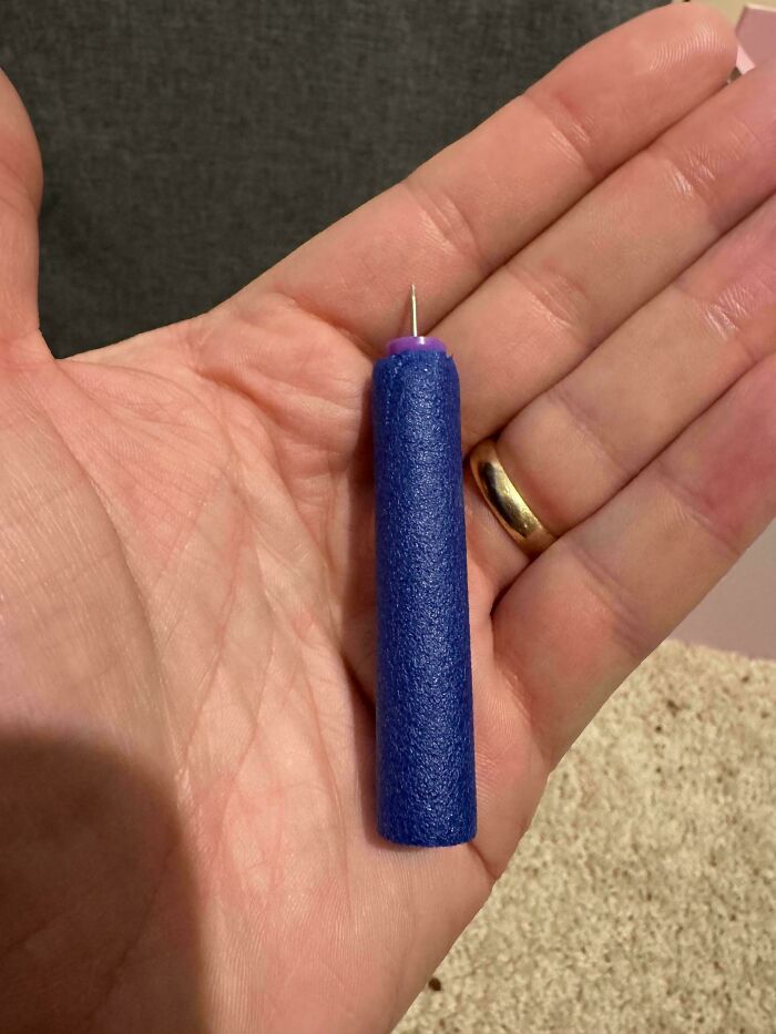 A parent holding a dart with a pin stuck in it, a common parenting moment of discovering unexpected dangers.