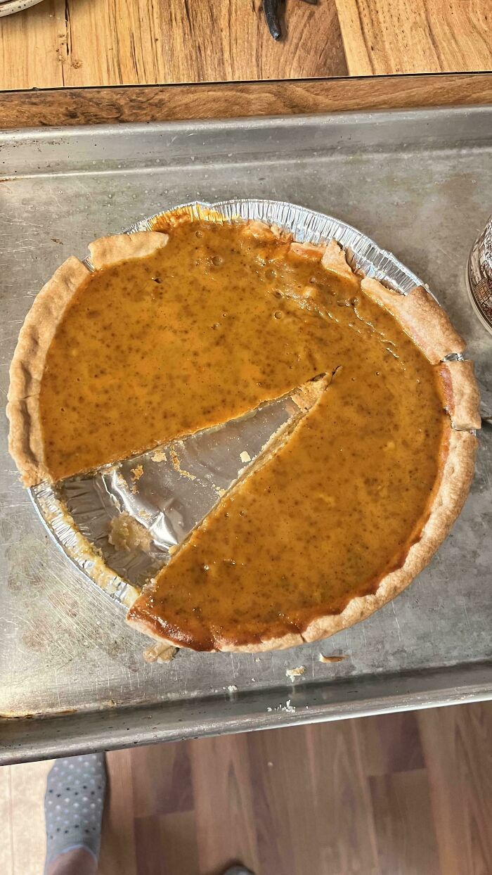 A partially eaten pumpkin pie on a metal baking sheet, making becoming a cat lady look more attractive.